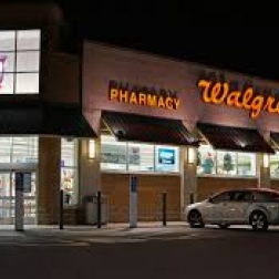 Walgreens storefront at night with silver car parked in parking lot
