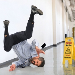 man slipping and falling next to "Wet Floor" sign