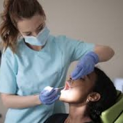 Dental hygienist performing teeth cleaning for female client