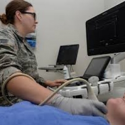 Female soldier performing ultrasound on patients shoulder