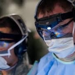 Doctors in surgical gowns wearing head lamps