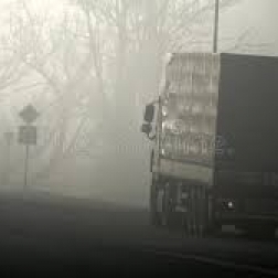 semi truck driving down foggy road