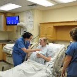 Pregnant woman in hospital bed talking with nurses